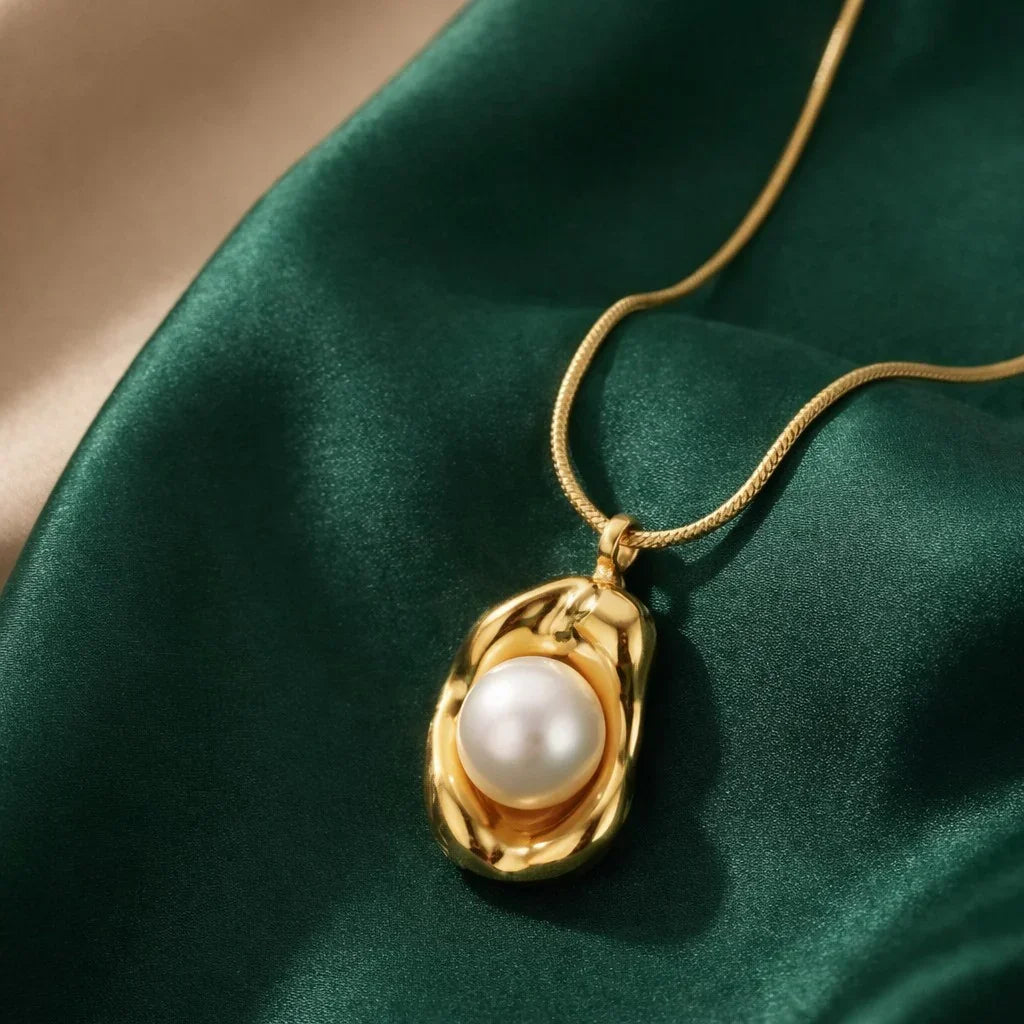 Gold stainless steel necklace with white pearl pendant on green satin fabric