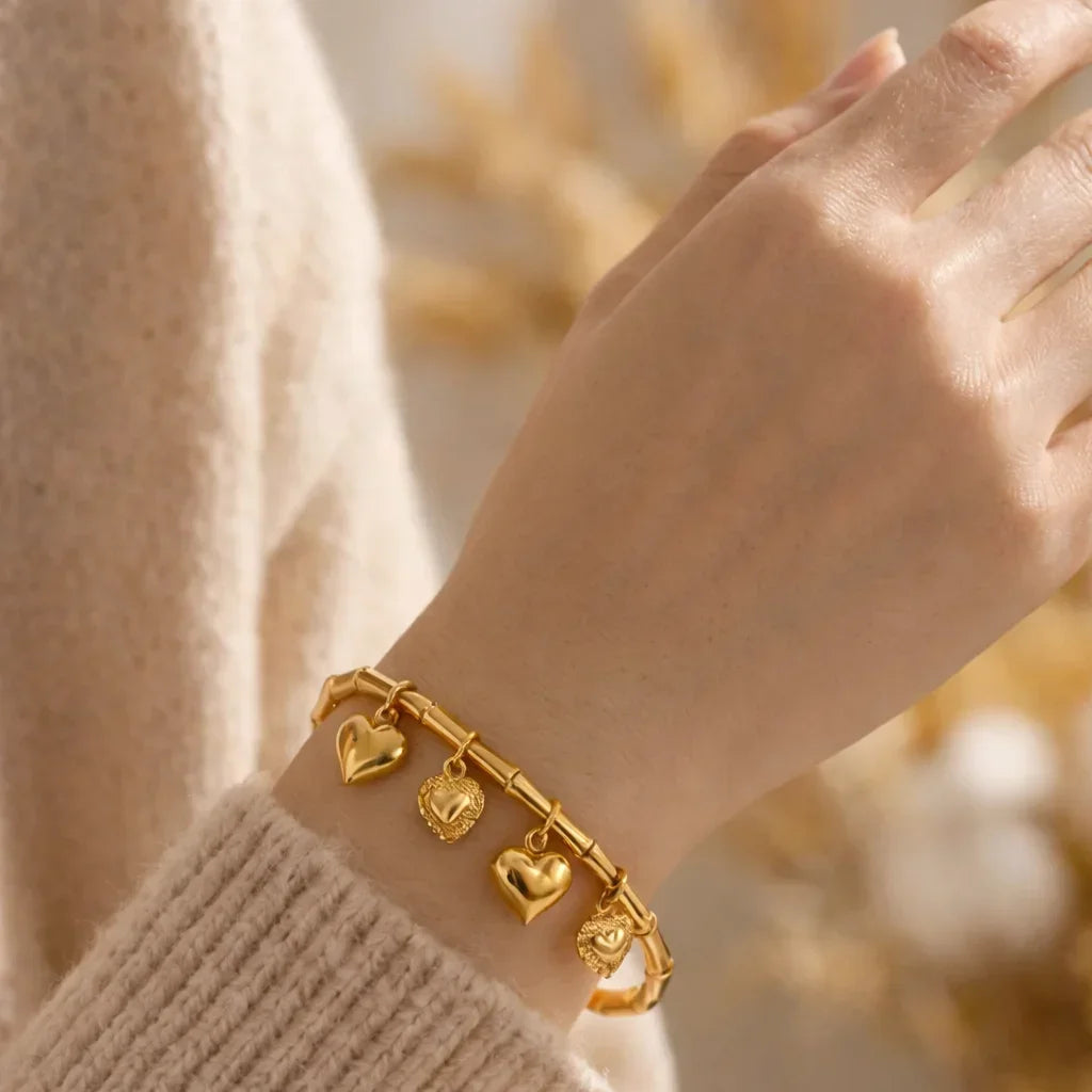 Gold stainless steel bracelet with heart charms on wrist, minimalist jewelry style